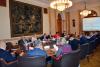 A szeminárium valamennyi résztvevője tanácskozásuk közben, amint a Kúria Mailáth-termének tárgyalóasztalánál ülnek.